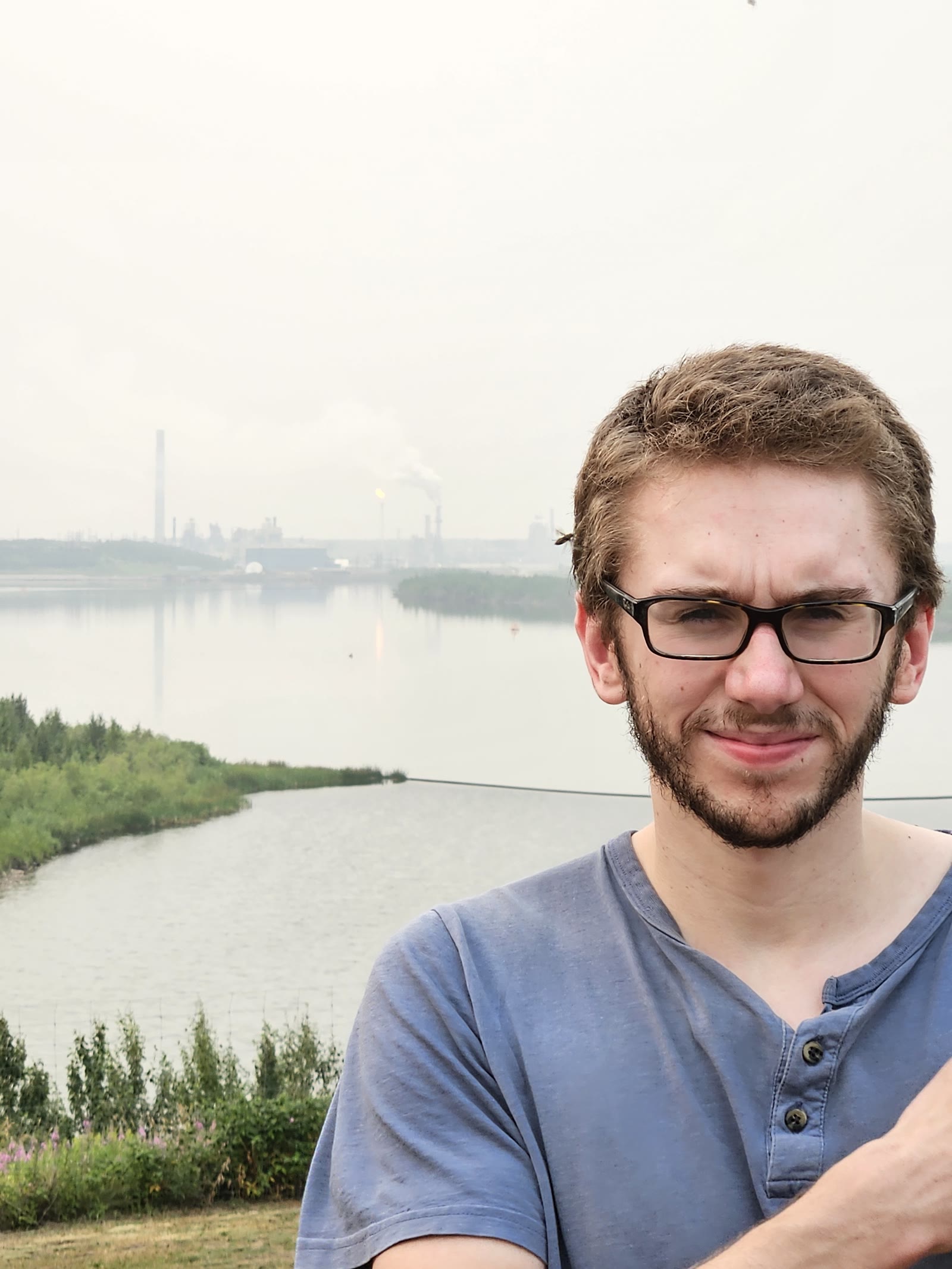 Neil beside water and an industrial plant